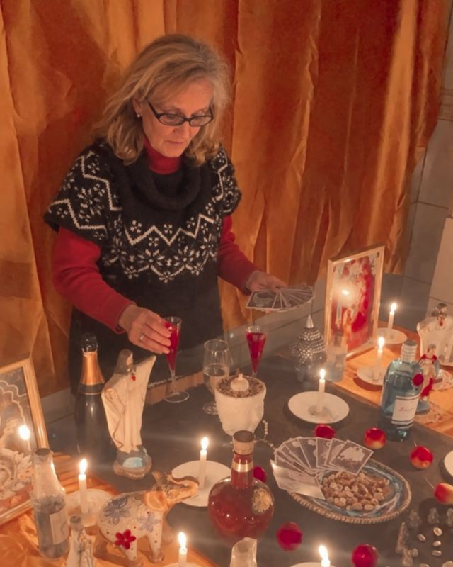 Tamara Lynch trabajando en su altar, con velas, cartas e imágenes
