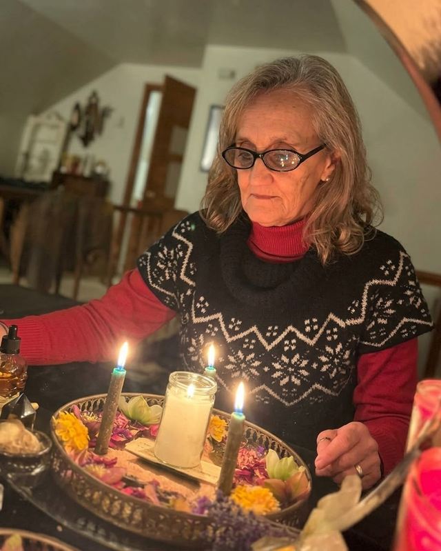 Tamara Lynch preparando un trabajo a la luz de las velas, con flores